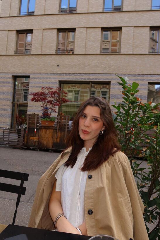 Portrait einer Creatorin im Trenchcoat vor einem Café